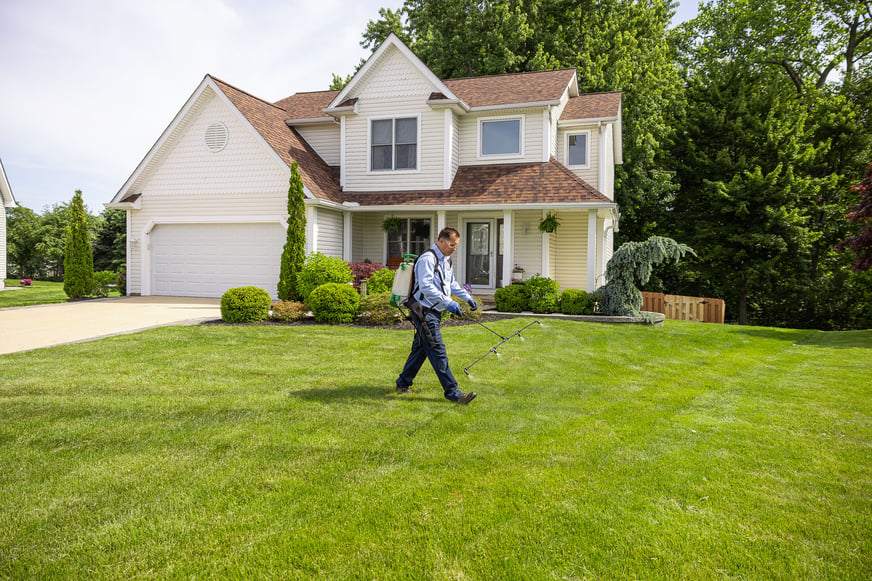 lawn care technician applying weed control to front yard