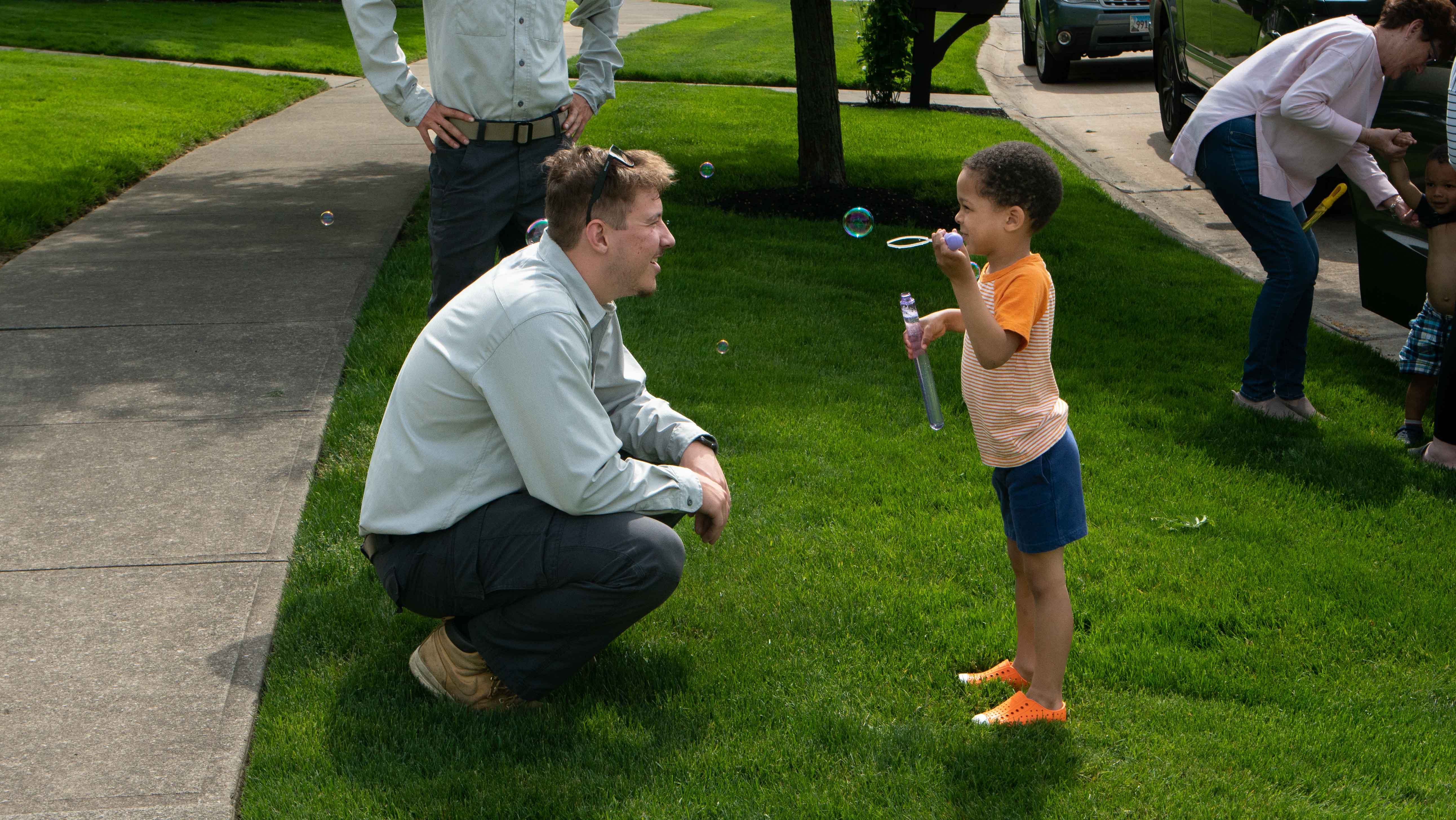 technician with child blowing bubble on green lawn