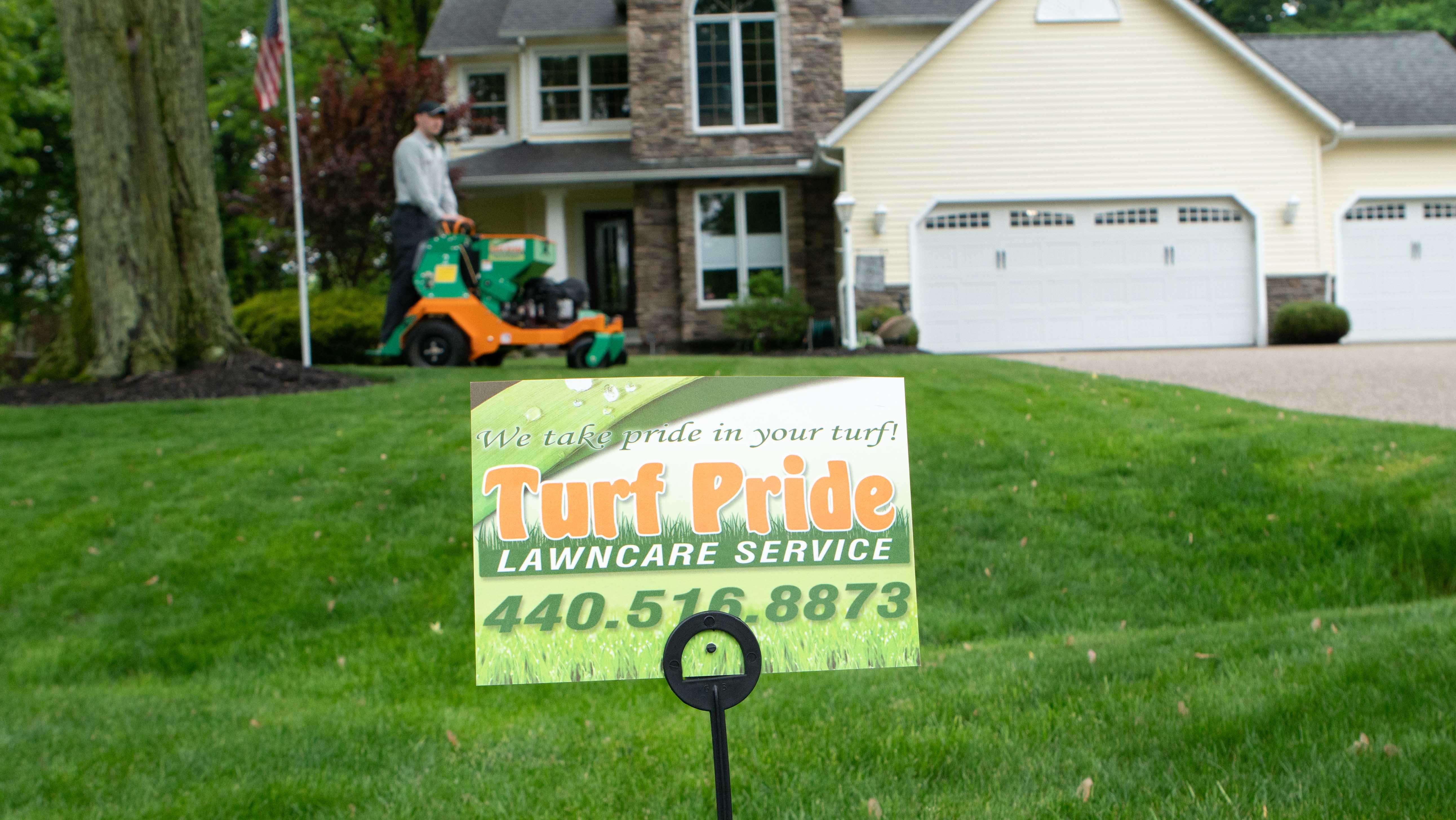 Technician on machine with turf pride sign up front customer front yard