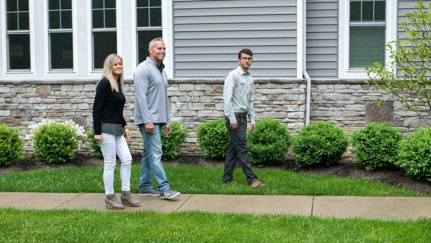 Technician-inspecting-lawn-with-homeonwers