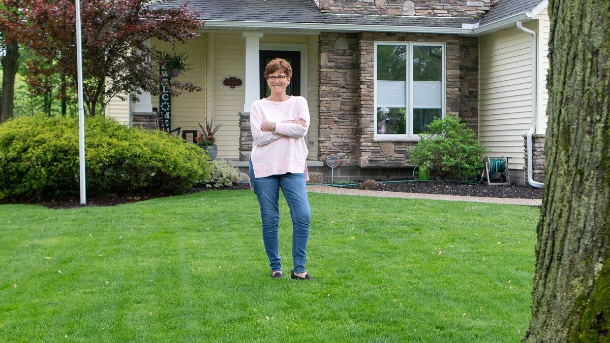 customer standing in front green lawn smiling 