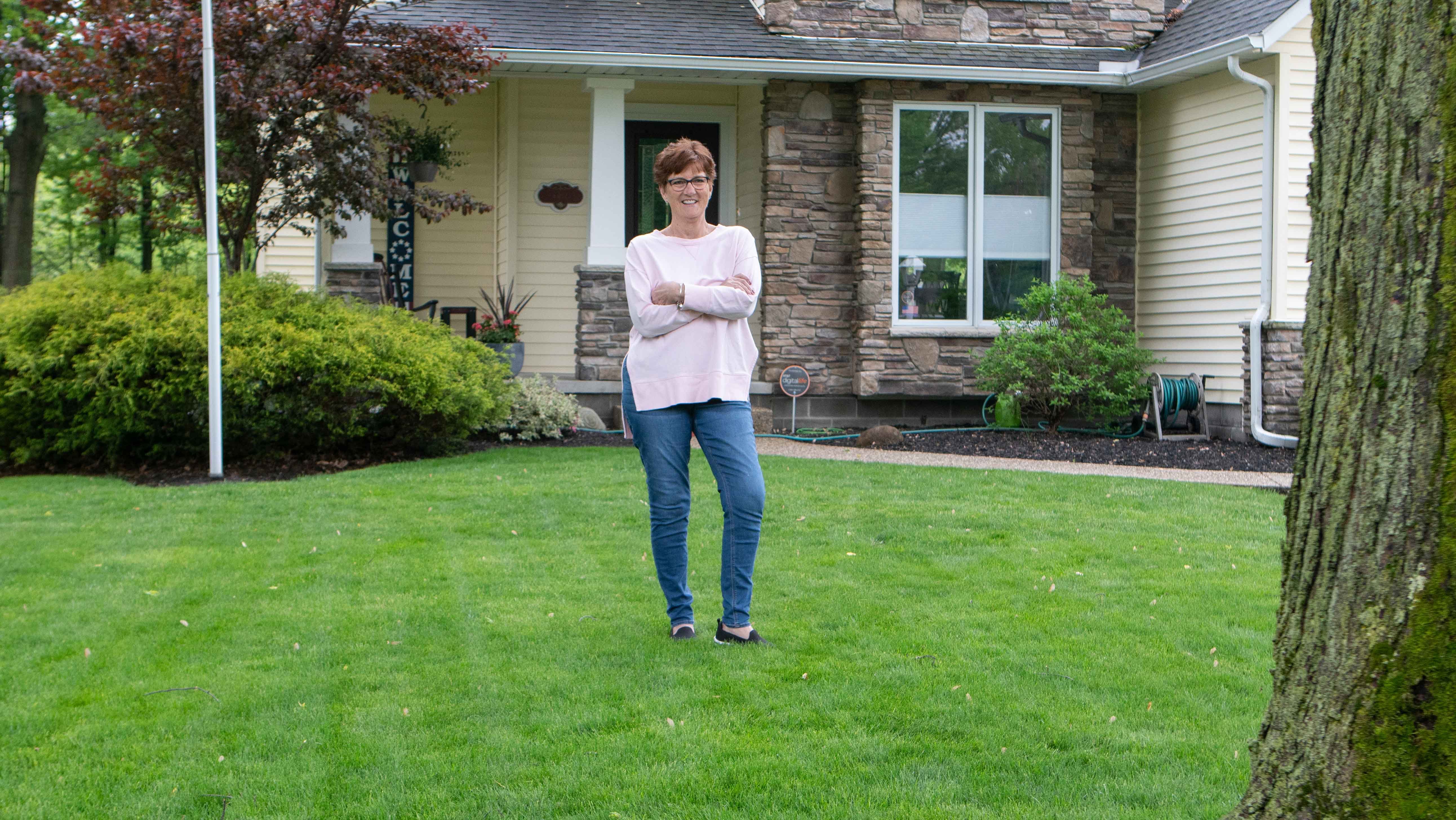 customer standing in front green lawn smiling 