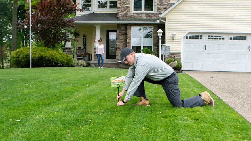 Turf Pride lawn care technician in yard with sign