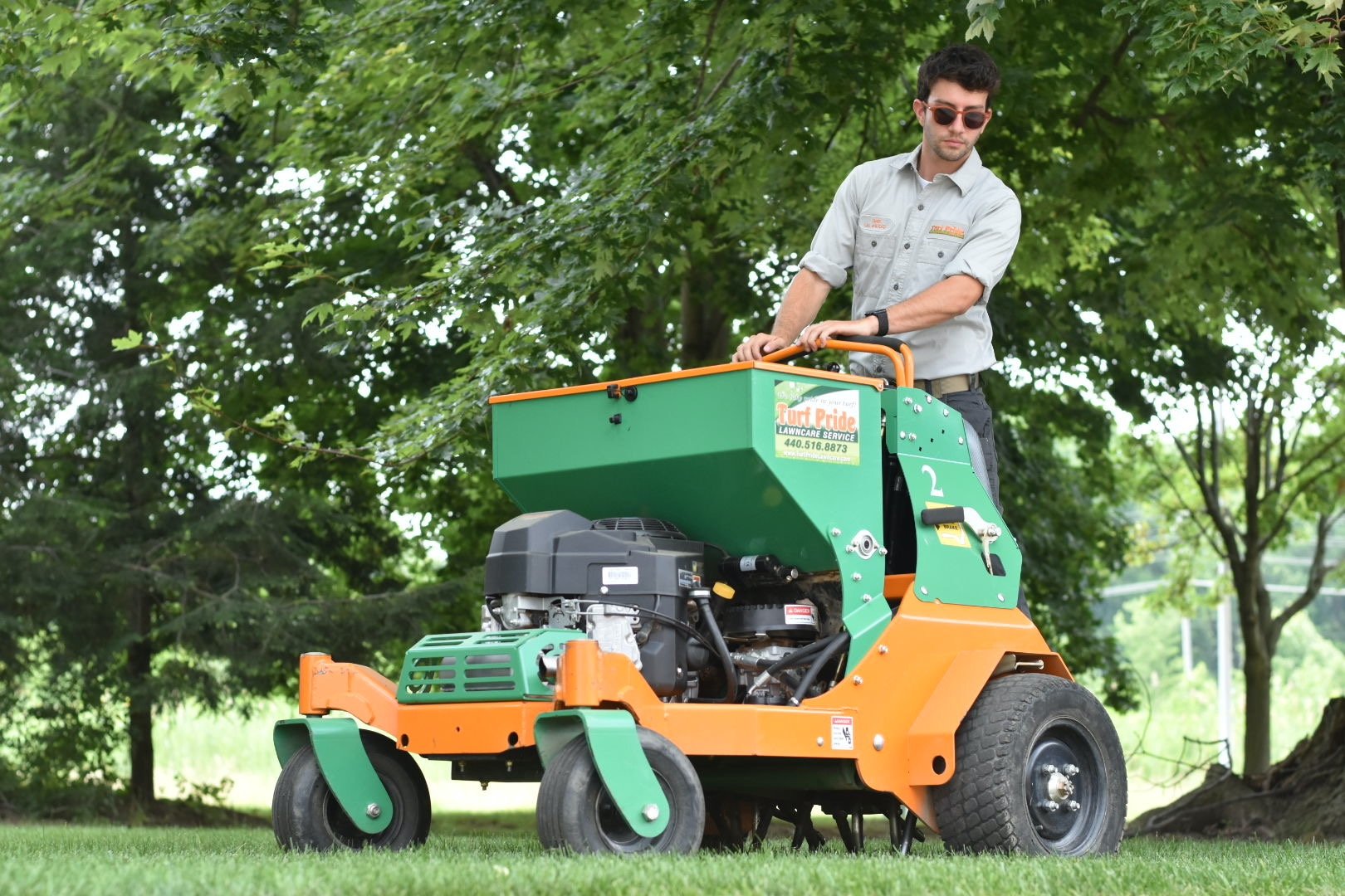 Technician riding machine aerating lawn 