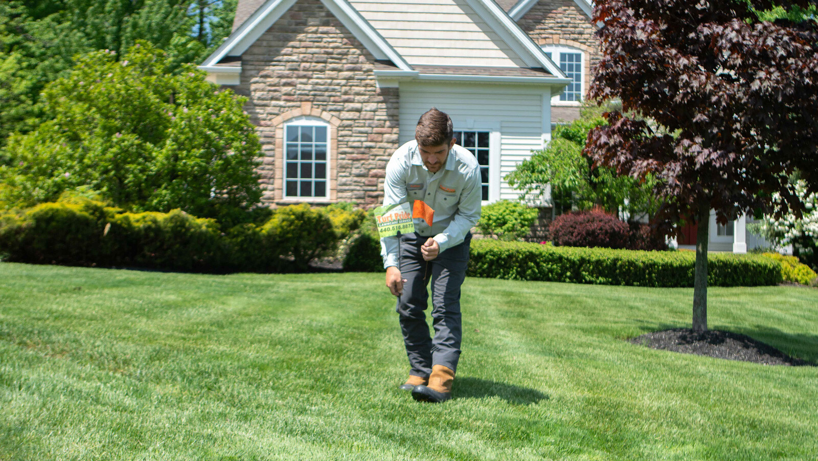 Turf Pride Lawn care technician putting sign in green grass