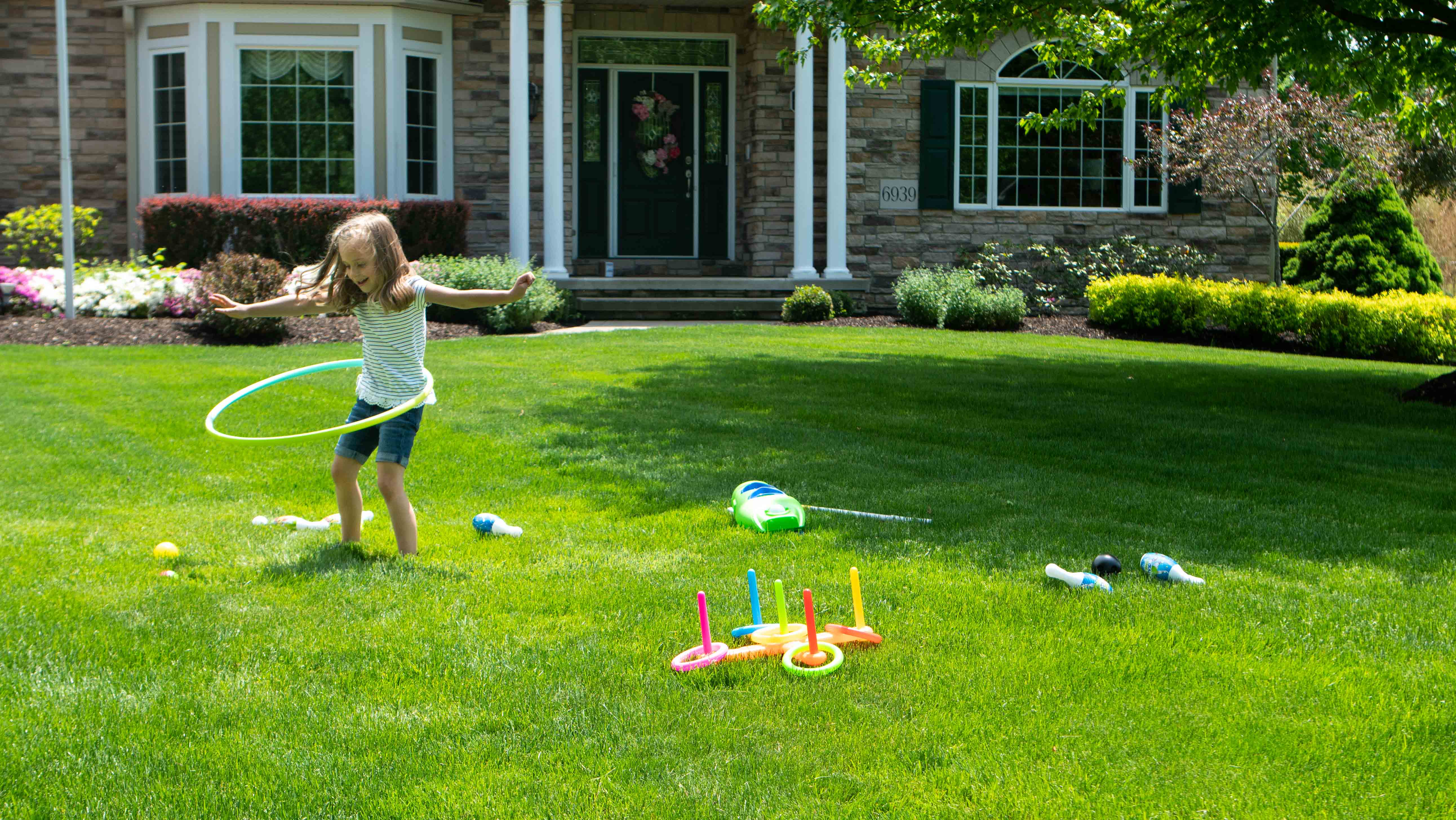 little girl playing in front yard green grass