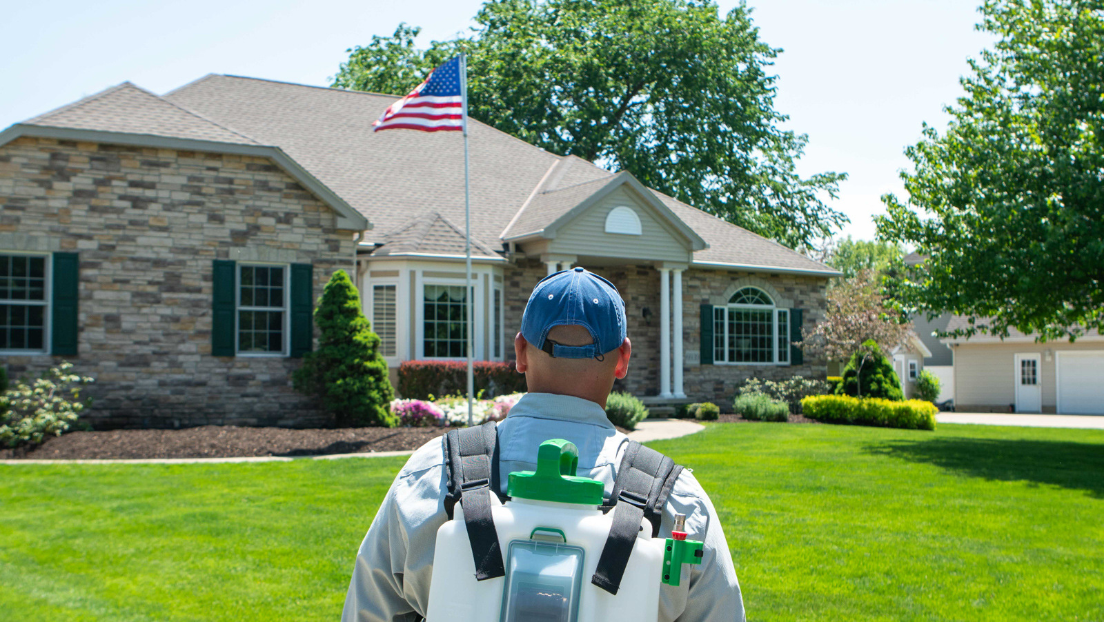 team member walking towards house to spray for bugs