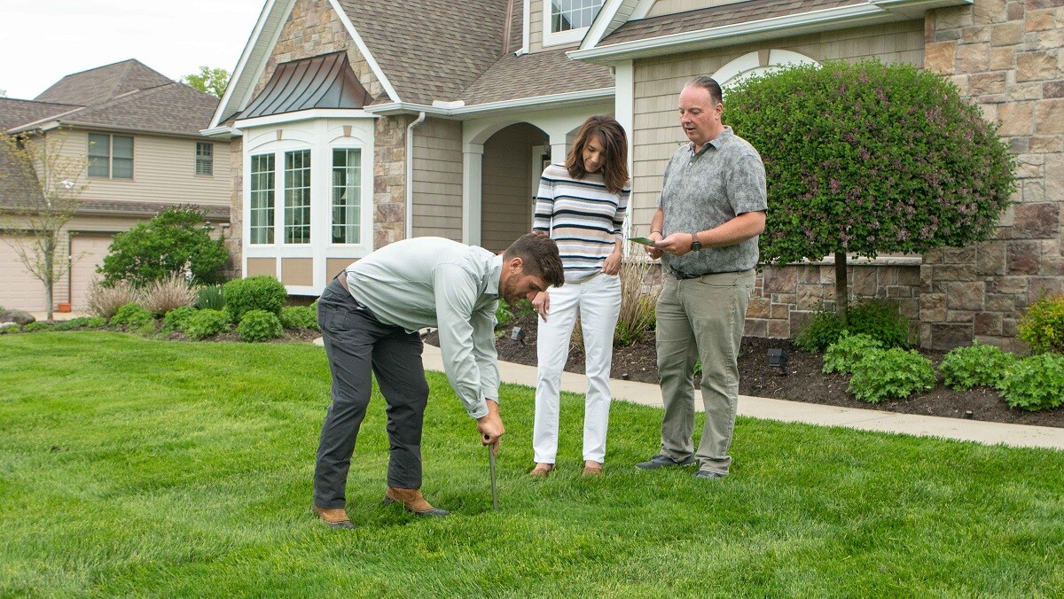 technician on lawn with customers looking at grass